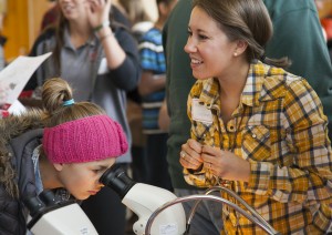 A girl peers through a microscope during one of University of Utah's 2014 Science Day's workshops.