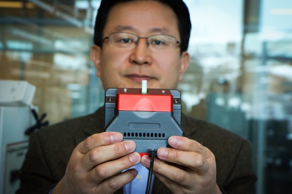 University of Utah materials science and engineering professor Ling Zang holds up a prototype handheld detector his company is producing that can sense explosive materials and toxic gases. His research team developed a new material for the detector that can sense alkane fuel, a key ingredient in such combustibles as gasoline, airplane fuel and homemade bombs.