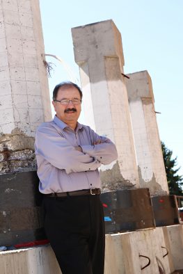 University of Utah civil and environmental professor Chris Pantelides stands next to a donut-sized "repair" he and a team of researchers designed that can fix a damaged column on a bridge. The repair — a black concrete donut surrounding the ends of the column and wrapped with a composite fiber material — can be deployed on bridges damaged in an earthquake much more quickly than through the standard procedure.